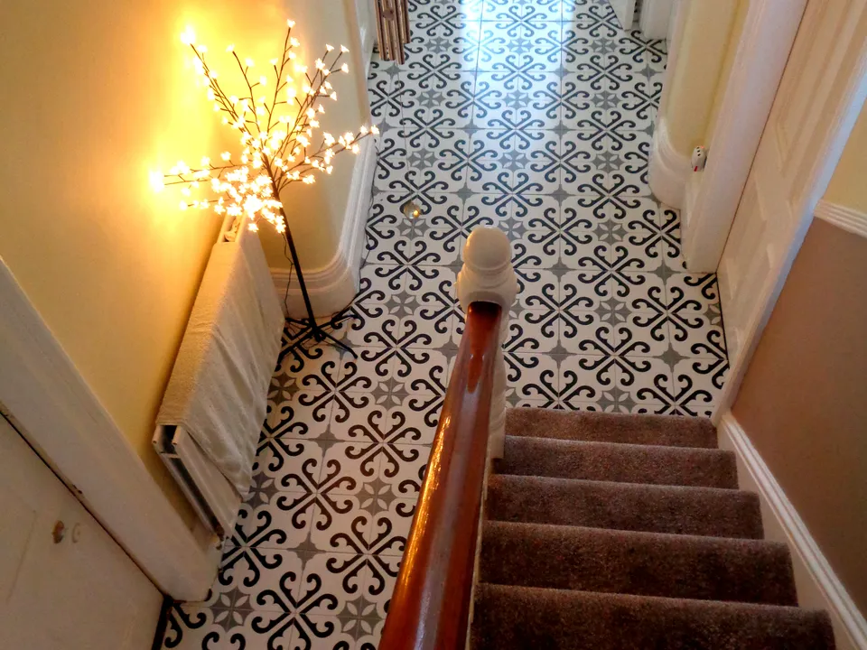 A hall we tiled: a black and white patterned floor, seen from the top of the stairs
