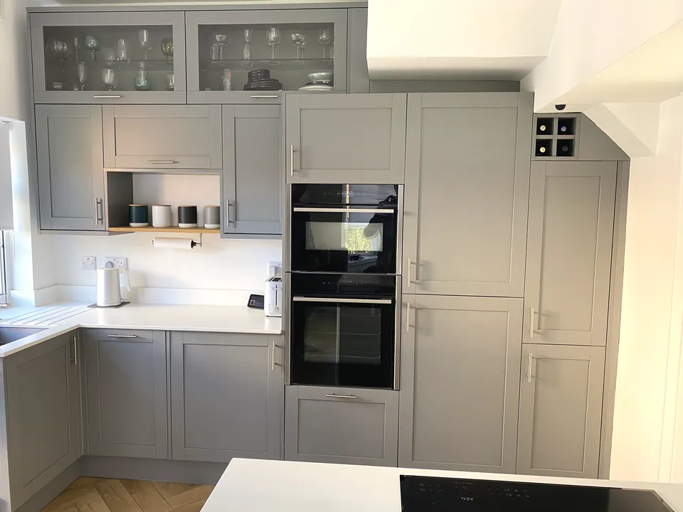 The kitchen we fitted: grey shaker units, a wall of tall cupboards with two built-in ovens, white worktops and an island
