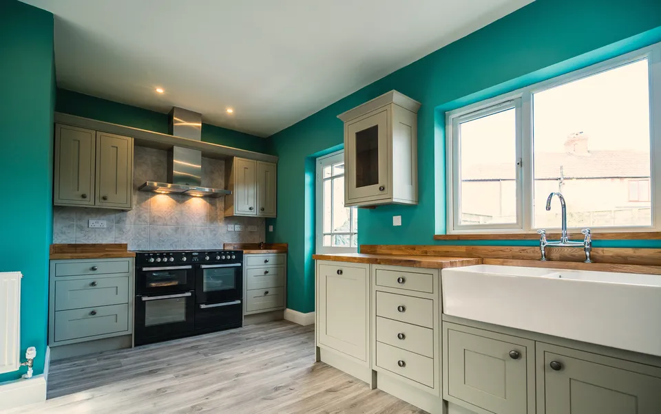 A kitchen we fitted: teal walls, sage shaker units, oak worktops, a range cooker and a Belfast sink