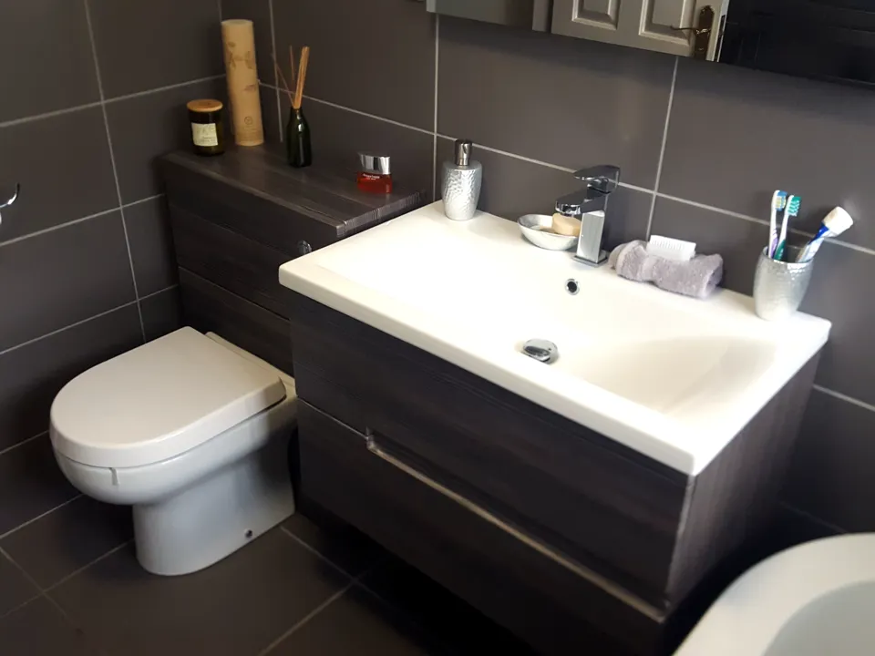 Wide white basin on a wall-hung drawer vanity beside a back-to-wall WC, in graphite tiles