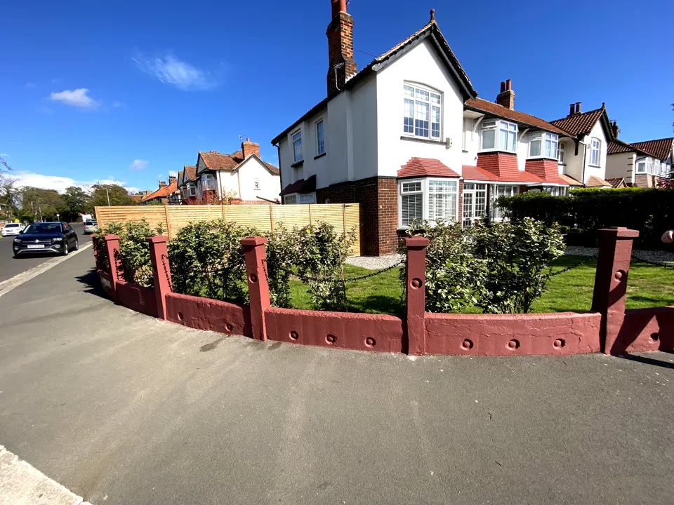 Corner front garden wall painted heritage red in front of a 1930s house