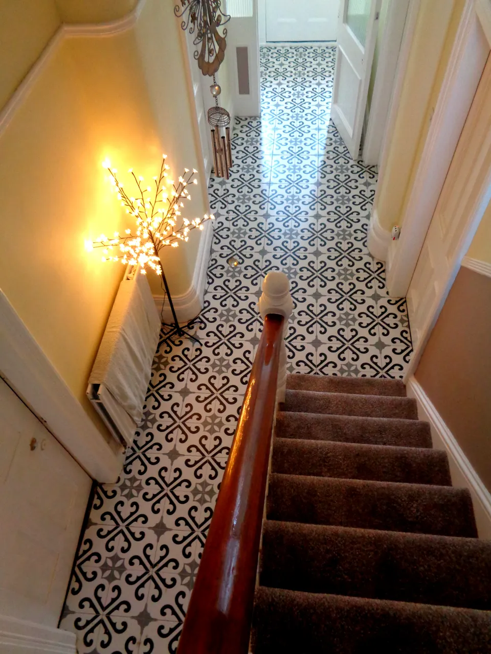 Hallway floor in black, grey and white Victorian-style patterned tiles, seen from the top of the stairs