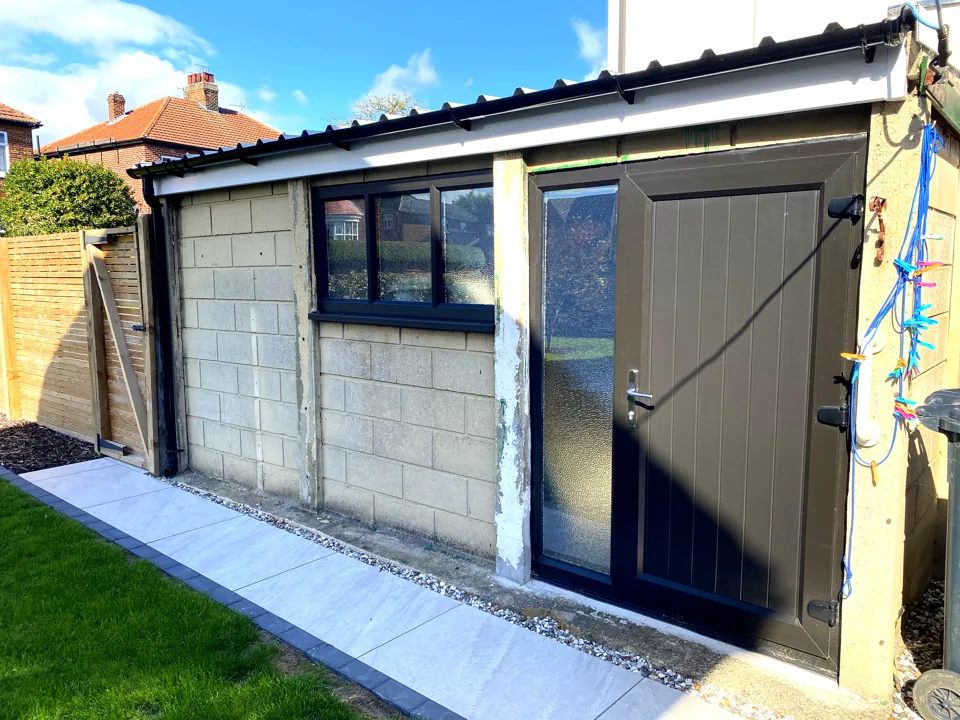 Garage with a new anthracite door and glazed side panel, a dark-framed window and a porcelain path