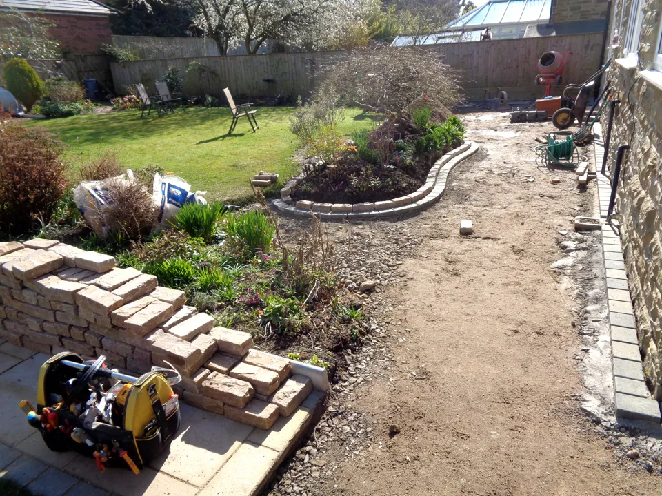 Before: the side of the house dug out, with walling stone stacked ready for the raised bed