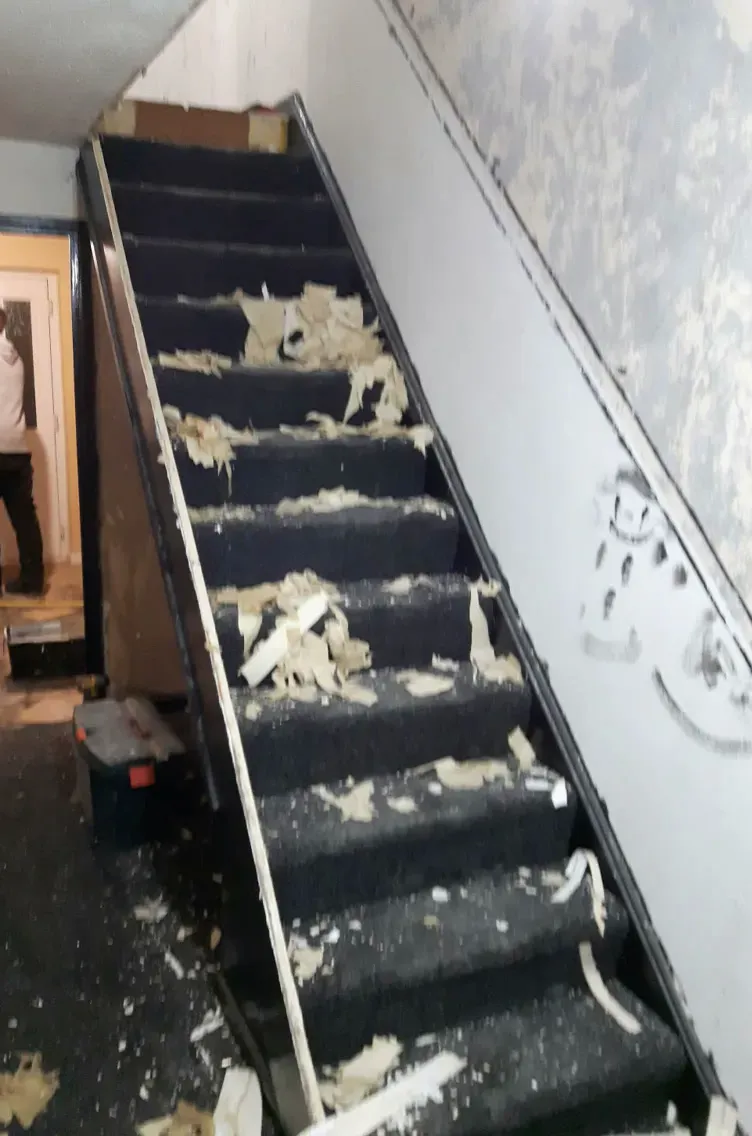 Before: the staircase stripped of its old dark carpet, with torn underlay and bare walls